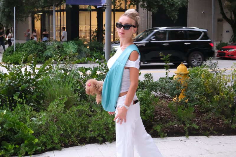 A woman walking a city street with her poodle riding head-out in the Aquamarine carrier.
