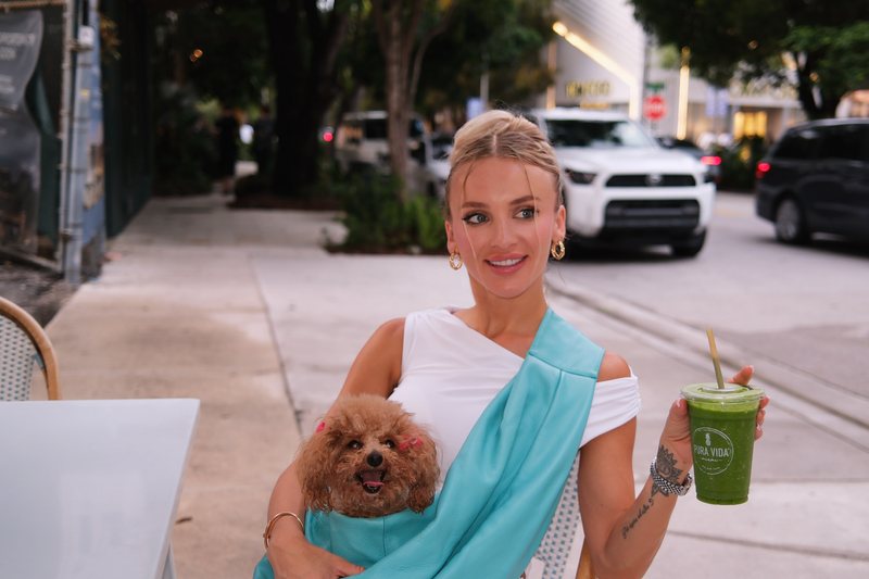 Seated at a pavement cafe with a drink, the poodle riding along in the carrier.